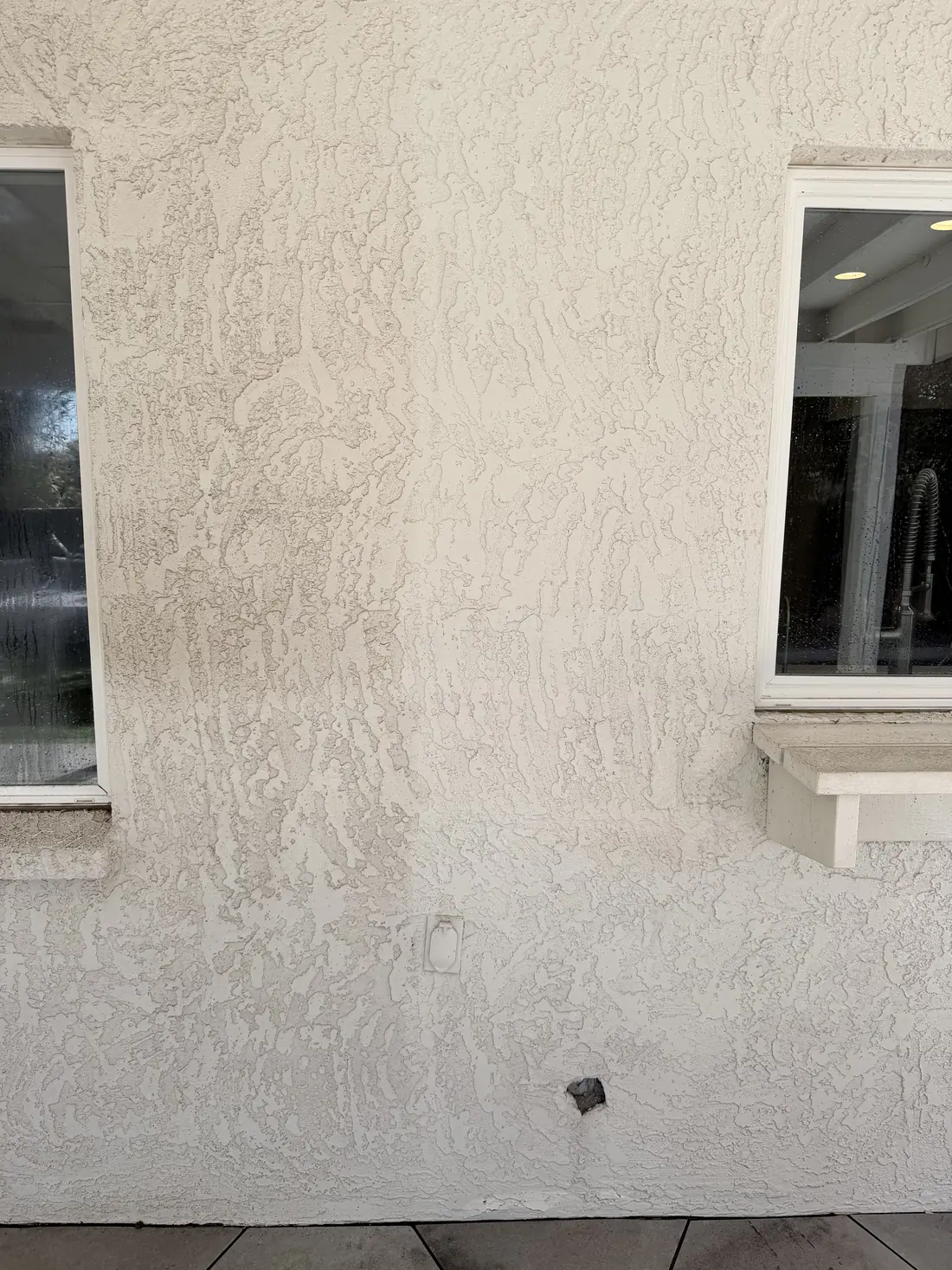 Stucco wall showing a clear line between soft washed and unwashed sections