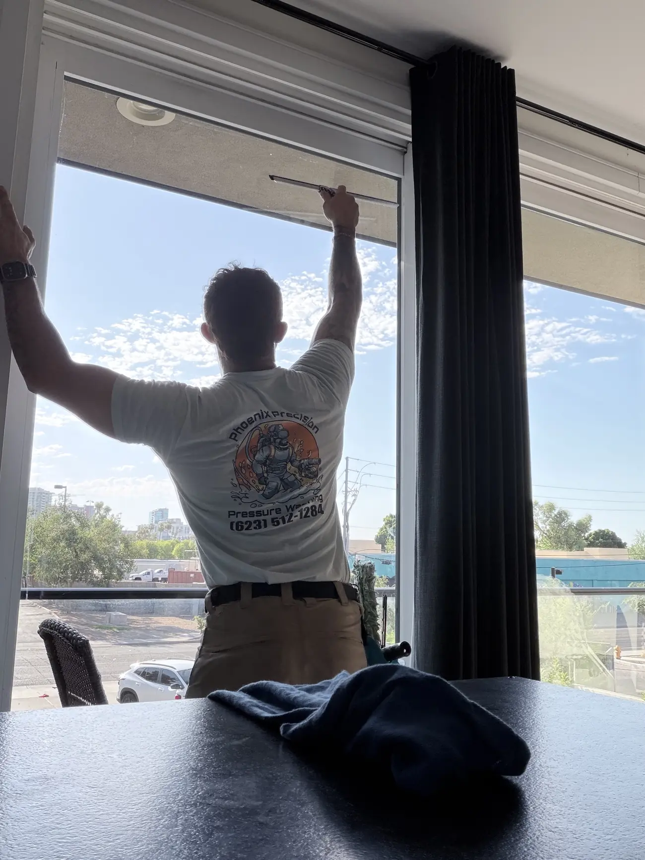 Phoenix Precision technician squeegeeing a large window from the inside of a high-rise unit